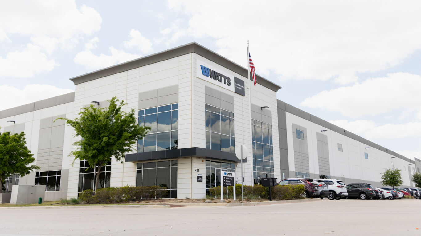 Woman holding a tablet while two men reference a document in the background